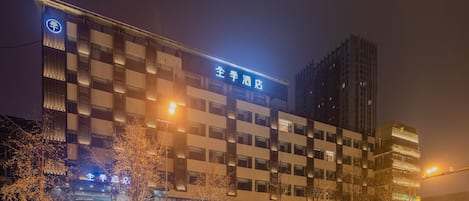 A hotel building with multiple floors, illuminated signage, and a modern architectural design.