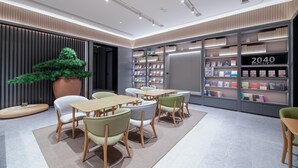 A modern library interior with bookshelves, seating, and a decorative tree. - Ji Hotel (Chengdu)
