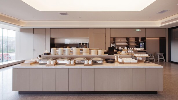 A modern kitchen with a central island, built-in appliances, and a large window. - Ji Hotel (Yantai)