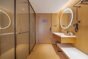 A modern bathroom with a glass shower enclosure, a vanity with a mirror, and a hairdryer. - Ji Hotel (Yantai)
