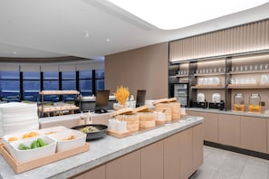 Eine moderne Küche mit Aussicht, ausgestattet mit einem Buffet und verschiedenen Speisen sowie einer Kaffeestation.
