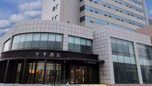 A hotel building with a modern design, featuring a prominent entrance with glass doors and a sign indicating it is a hotel. - Ji Hotel (Yantai)