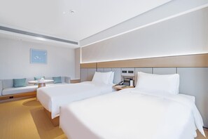 Ein Hotelzimmer mit zwei Betten, einem kleinen Tisch, einer Couch und einem an der Wand befestigten Telefon.