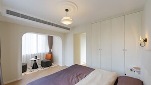 Ein Hotelzimmer mit Bett, einer Sitzecke mit Tisch und Stühlen, einem Kleiderschrank und einem Fenster mit Vorhängen.