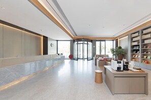 Eine moderne Lobby mit einer Drehtür, einer Kaffeestation und einem Bücherregal.