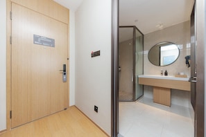 A hotel room with a wooden door, a bathroom with a round mirror, and a modern design. - Ji Hotel (shaoxing Shangyu Economic Development Zo (Shaoxing)
