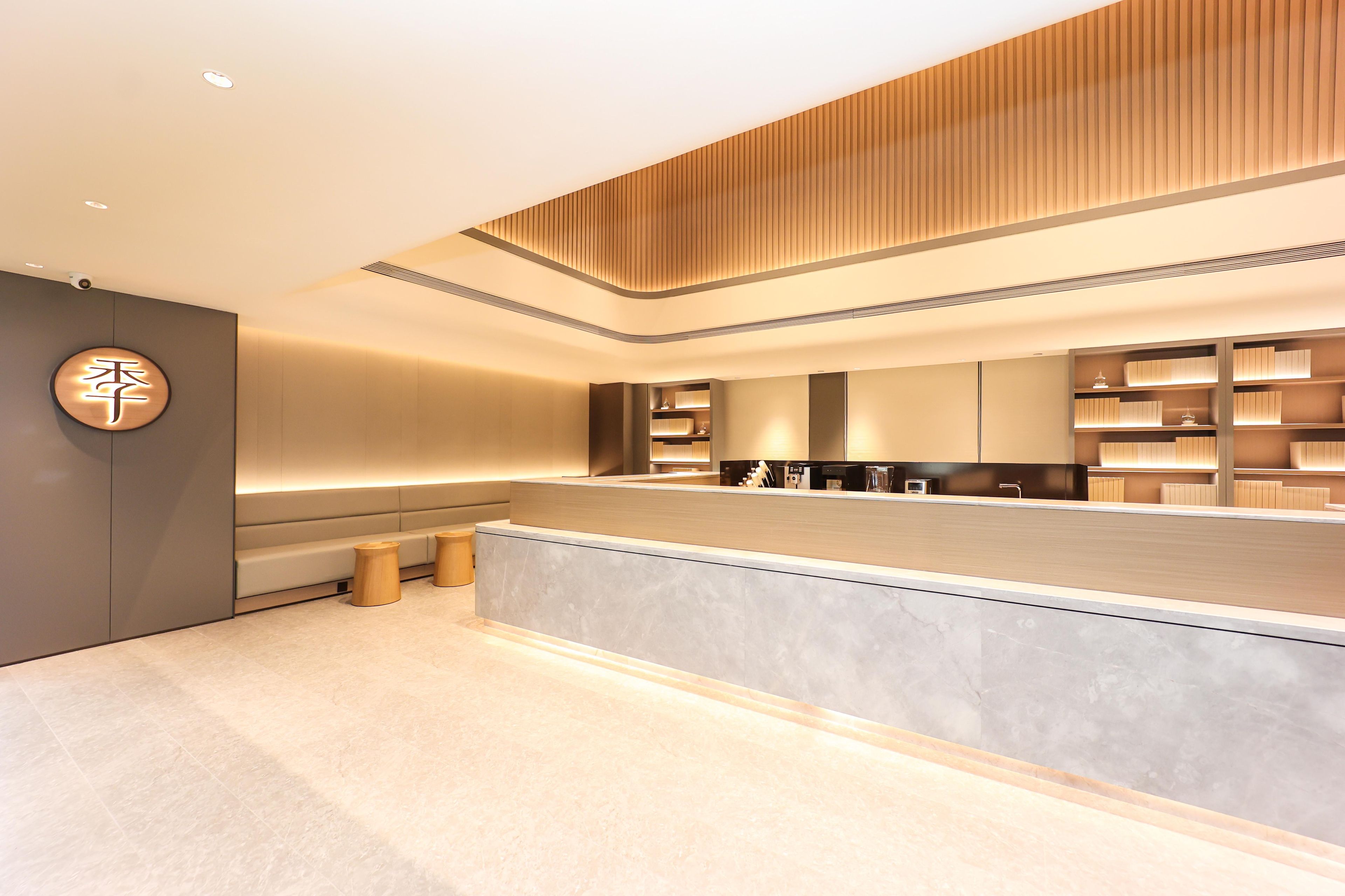 Un área de recepción moderna con techo de madera, mostrador de recepción y señalización en la pared.