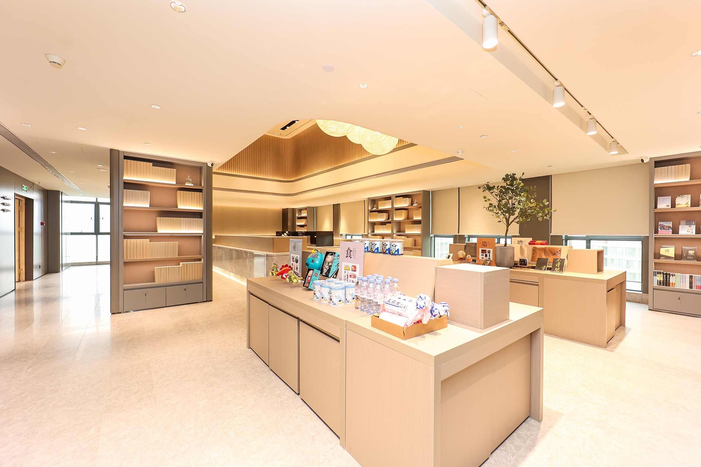 A modern hotel lobby with a central reception desk, built-in shelving, and a large window.