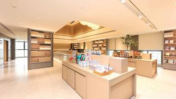 A modern hotel lobby with a central reception desk, built-in shelving, and a large window.