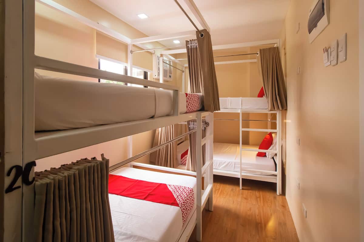 Una habitación con literas, una ventana con cortinas y un termostato en la pared.