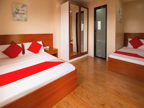 A hotel room with two beds, each with a wooden headboard, white bedding, and red pillows. There is a mirror on one wall and a door leading to another room. - OYO 832 The Teepee Place Hostel & Residence Inn (Cebu City)