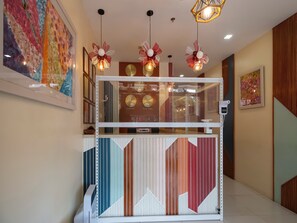A reception desk with a modern design, featuring a geometric patterned backdrop and decorative lighting fixtures. - OYO 832 The Teepee Place Hostel & Residence Inn (Cebu City)