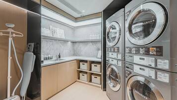 Un moderno cuarto de lavandería con varias lavadoras, una secadora y un aspirador.