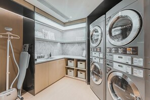 A modern laundry facility with multiple washing machines, a drying machine, and a vacuum cleaner. - Ji Hotel (Shanghai)