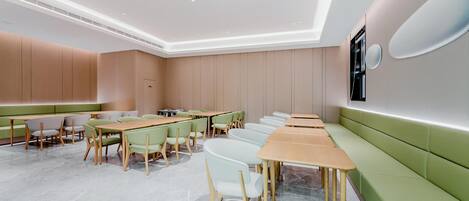 A modern conference room with green seating, wooden tables, and a white ceiling.