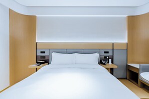 A modern hotel room with a large bed, bedside tables, a desk, and a chair. - Ji Hotel (Shanghai)
