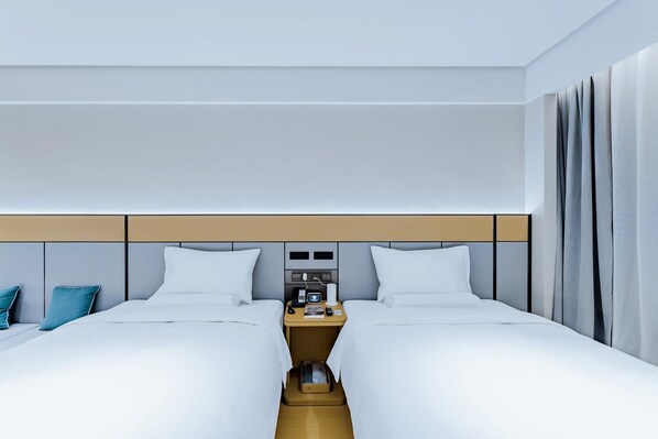 A hotel room with two beds, a nightstand, and a headboard with built-in controls.
