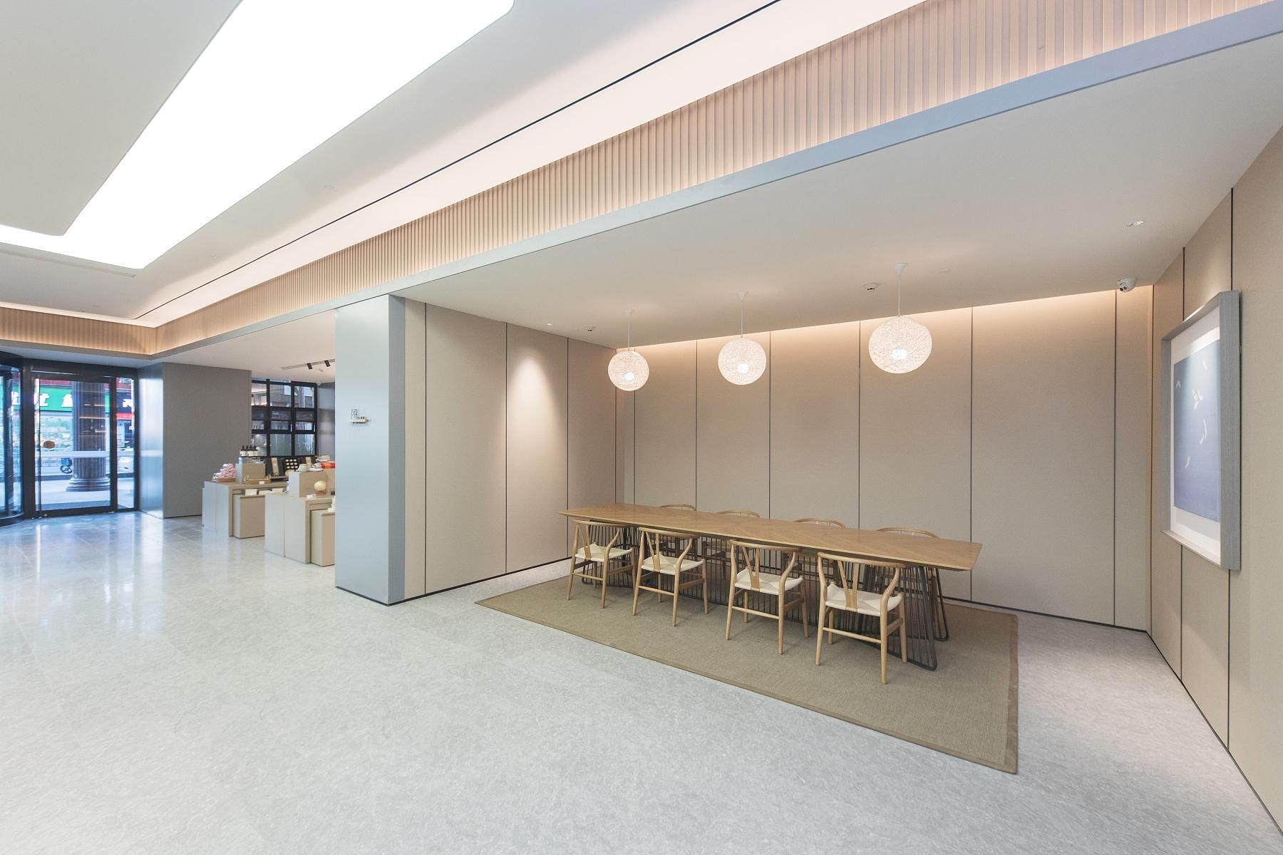 A modern interior with a long wooden table and chairs, a large window, and a minimalist design.