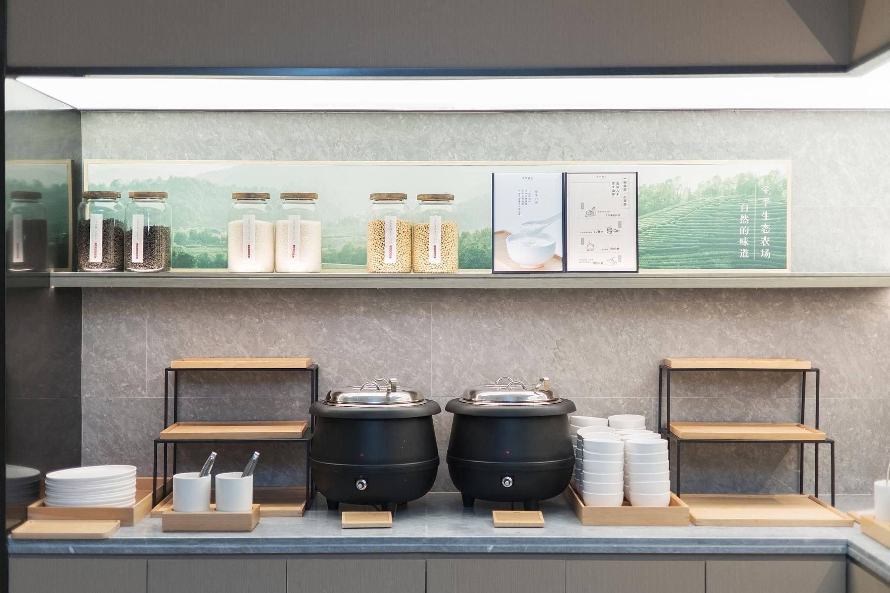 A buffet setup with jars of grains, a menu board, and two large cooking pots.