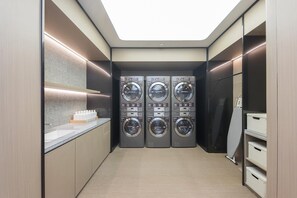 A laundry room with four stacked washing machines, a countertop with bottles, and a skylight. - Ji Hotel (Ningbo)