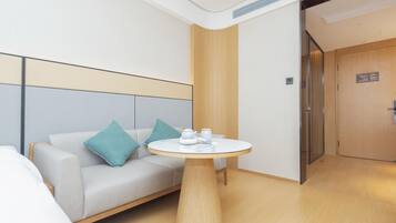 A modern hotel room with a sofa, a round table, and a wooden door.