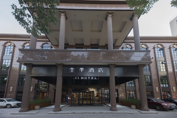 A hotel entrance with large columns, a covered entrance, and a sign reading 'JI HOTEL'. - Ji Hotel (Ningbo)
