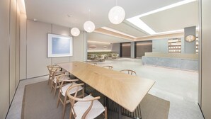 A modern conference room with a long table, chairs, and pendant lighting. - Ji Hotel (Ningbo)