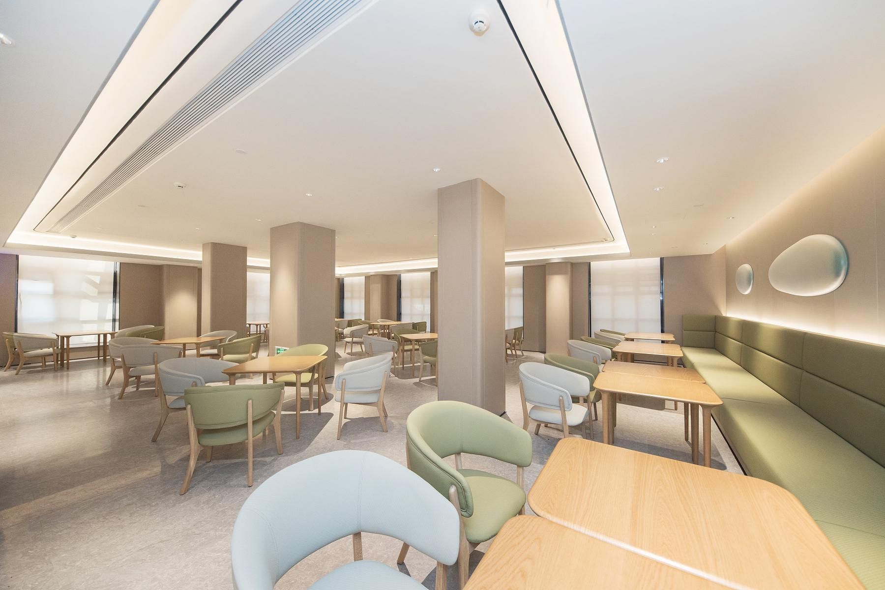 A modern interior with multiple seating areas, including tables and chairs, and a large pillar.
