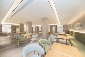 A modern interior with multiple seating areas, including tables and chairs, and a large pillar. - Ji Hotel (Ningbo)