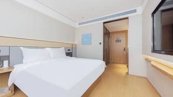 Ein Hotelzimmer mit einem großen Bett, Nachttischen, einem Flachbildfernseher und Holzboden.