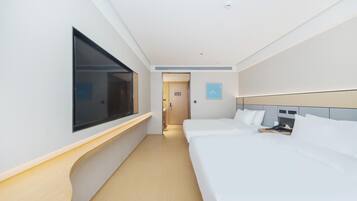 A hotel room with a large window, a bed, a bedside table, and a door leading to the hallway.