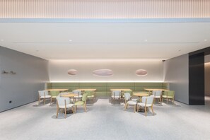 A modern interior with round tables and chairs, a green cushioned bench, and recessed lighting. - Ji Hotel (Ningbo)