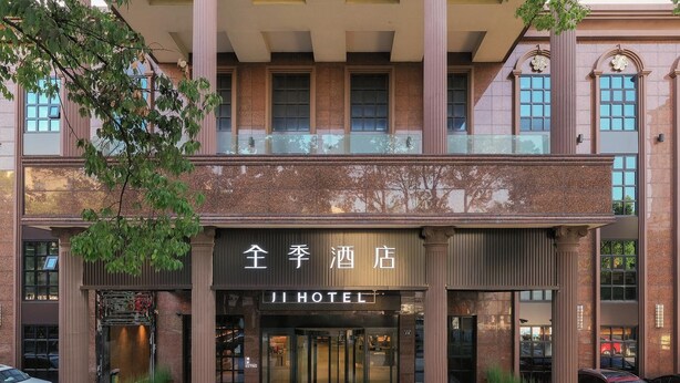 A hotel entrance with a modern facade, large glass doors, and a prominent sign. - Ji Hotel (Ningbo)