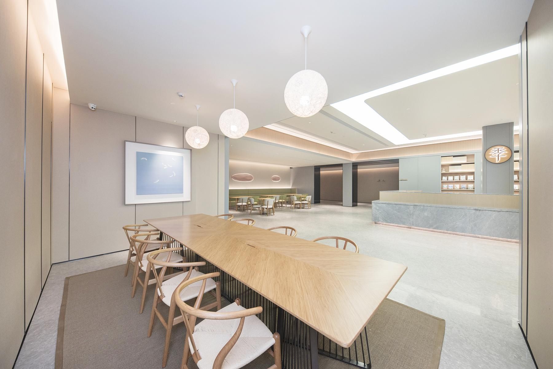 A modern conference room with a long table, chairs, and pendant lighting.