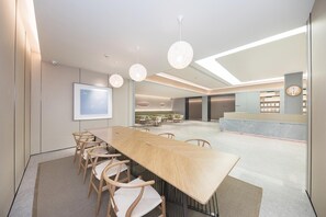 A modern conference room with a long table, chairs, and pendant lighting. - Ji Hotel (Ningbo)