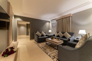A modern hotel room with a sofa set, a coffee table, and a decorative bench with flowers. - Enala Tabuk Hotel (Tabuk)