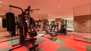 A gym with weight machines, a punching bag, and cardio equipment. - Enala Tabuk Hotel (Tabuk)