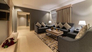A modern hotel room with a sofa set, a coffee table, and a decorative bench with flowers. - Enala Tabuk Hotel (Tabuk)