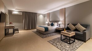 A hotel room with a bed, bedside table, lamp, sofa, and a TV. - Enala Tabuk Hotel (Tabuk)
