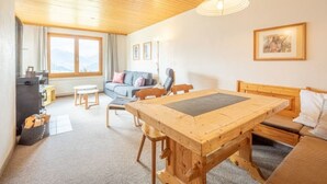 Ett mysigt rum med ett träpanelat tak, ett matbord, en soffa och ett fönster med utsikt.