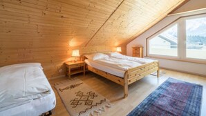 Ein Schlafzimmer mit Holzboden, zwei Betten, einem Fenster mit Blick und einem Teppich.