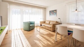 A modern living room with a sofa, a coffee table, a dining table with chairs, and a painting on the wall. - Val Signina 5-2 by Interhome (Laax)