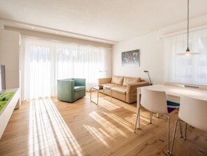 Ein modernes Wohnzimmer mit Sofa, Couchtisch, Esstisch mit Stühlen und einem Gemälde an der Wand.