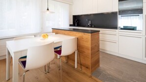 A modern kitchen with white cabinets, a wooden island, and a black countertop. - Val Signina 5-2 by Interhome (Laax)