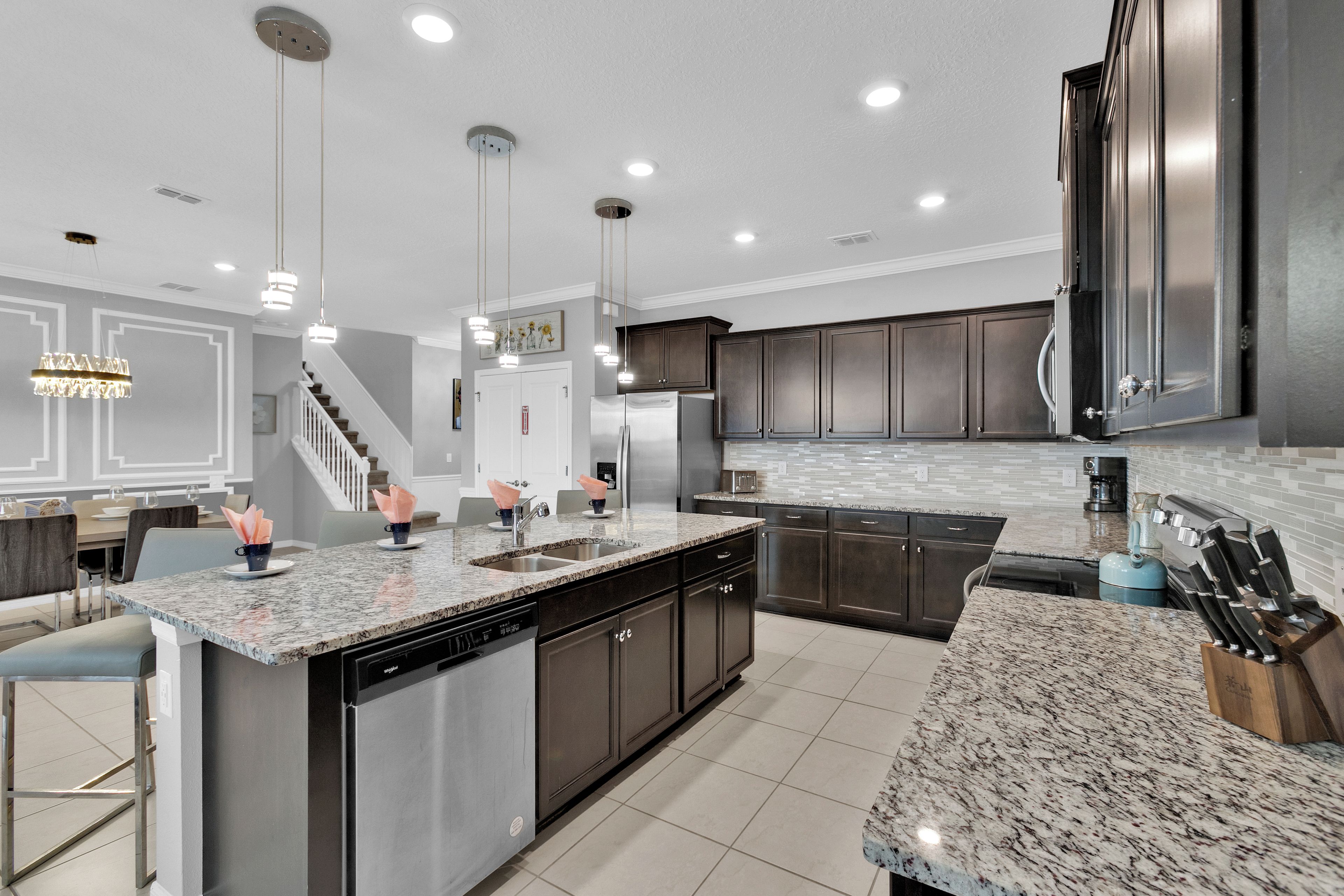A modern kitchen with a central island, stainless steel appliances, and a marble countertop.