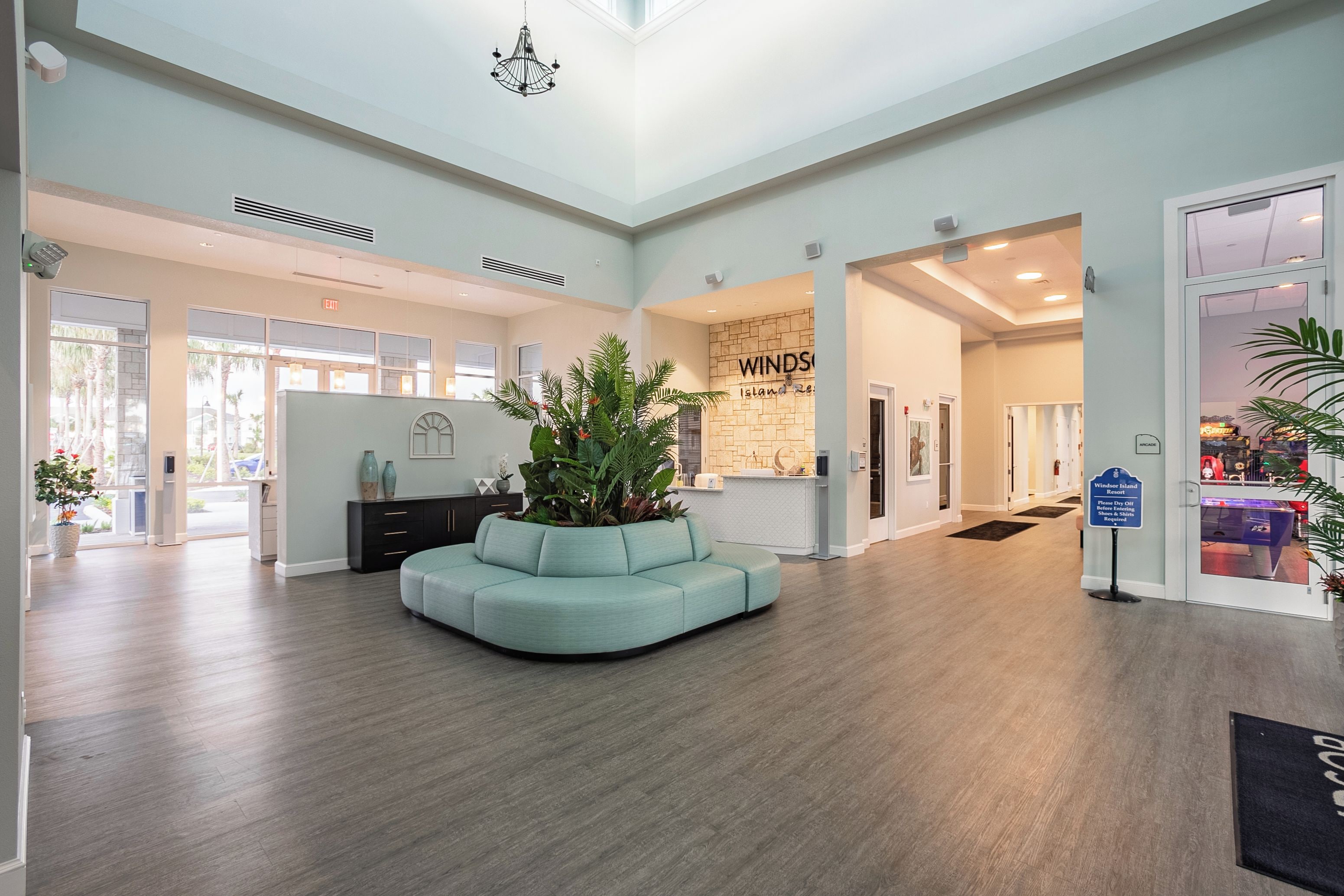 Een ruime lobby met een gebogen teal-kleurige bank, een receptiebalie en een bord met 'Windsor Island Resort'.
