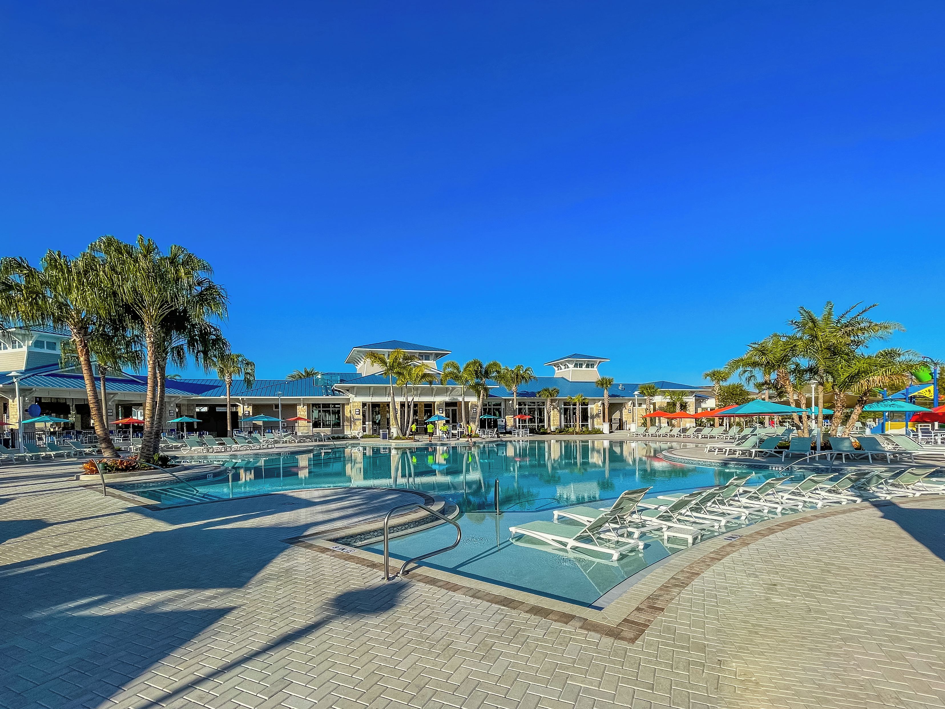 Une piscine de complexe hôtelier avec des chaises longues et des palmiers.