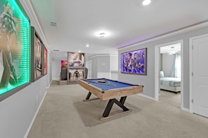 Una habitación con mesa de billar, cama y puerta que da a otra habitación.
