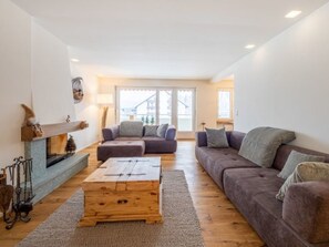 A living room with a fireplace, two sofas, a coffee table, and a view of the outside. - Val Signina 7-12 by Interhome (Laax)
