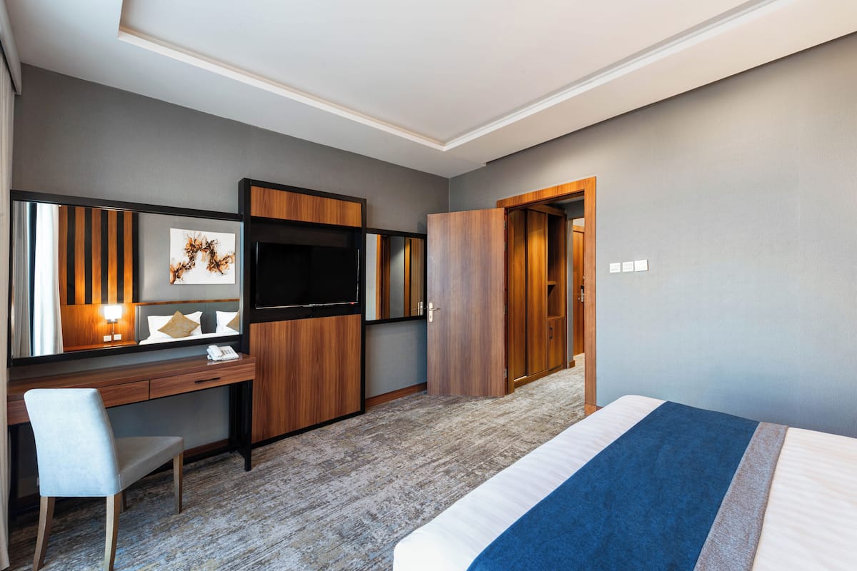 Une chambre d’hôtel comprenant un lit, un bureau avec une chaise, une télévision et une armoire.